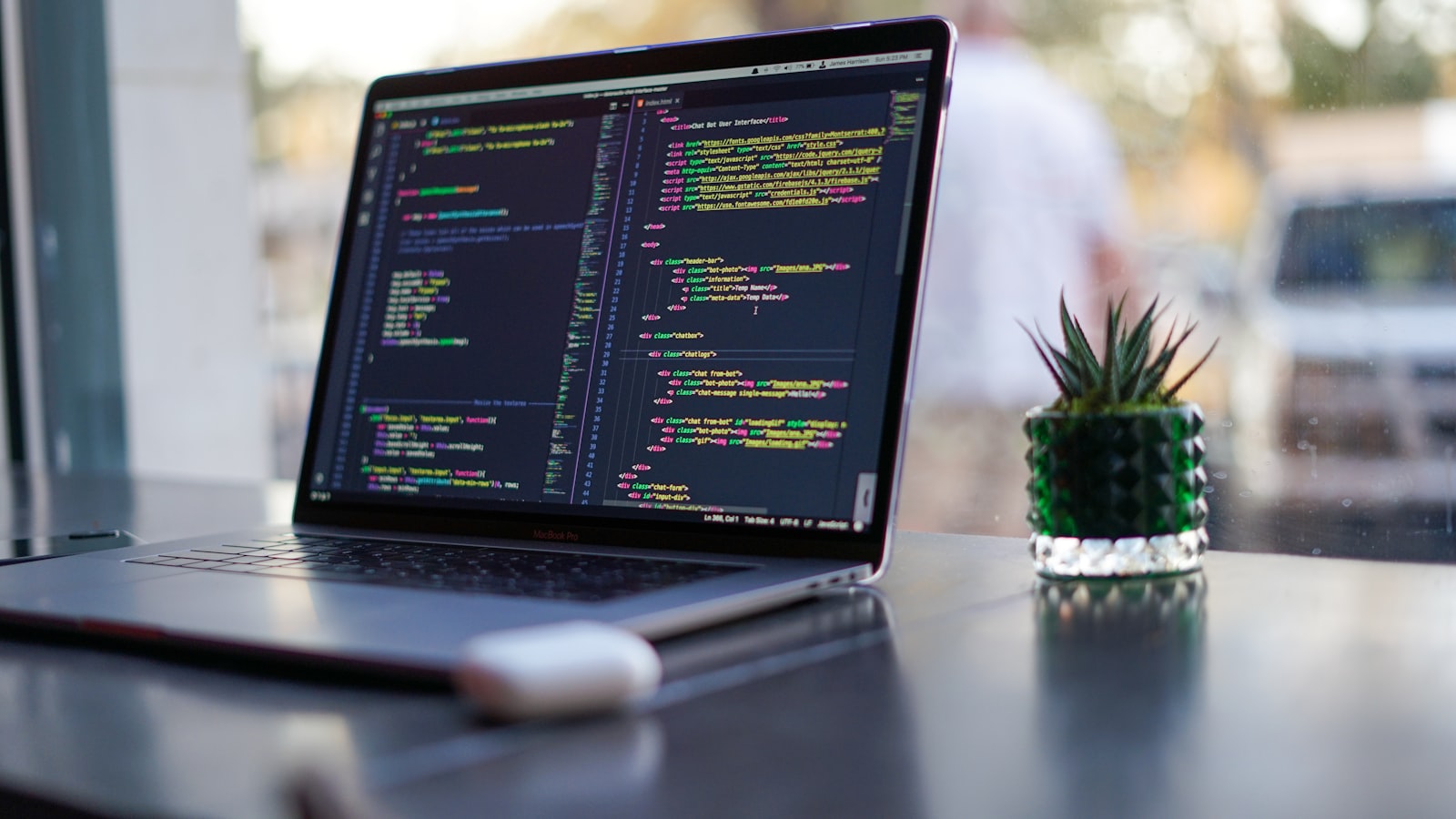 Laptop showing colorful TypeScript code beside a small cactus